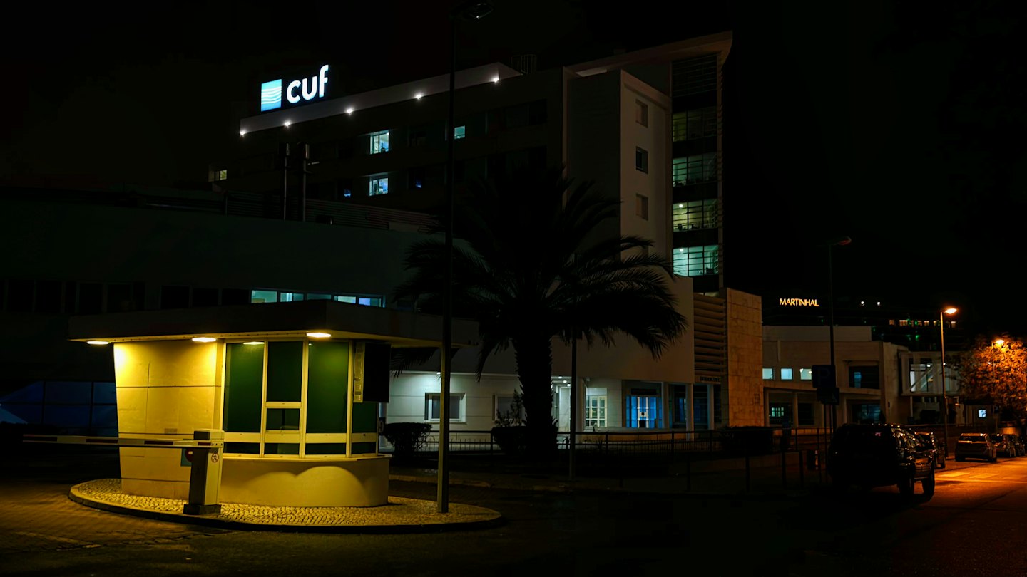Modern office building complex at night with a security booth.