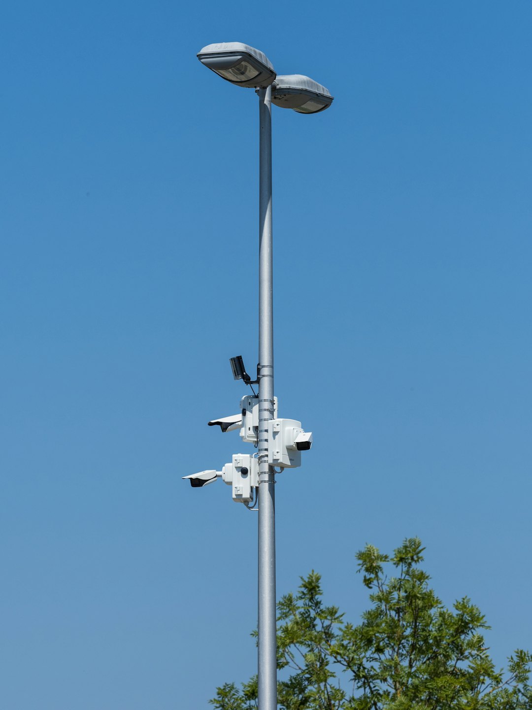 Streetlights and security cameras mounted on a tall metal pole.